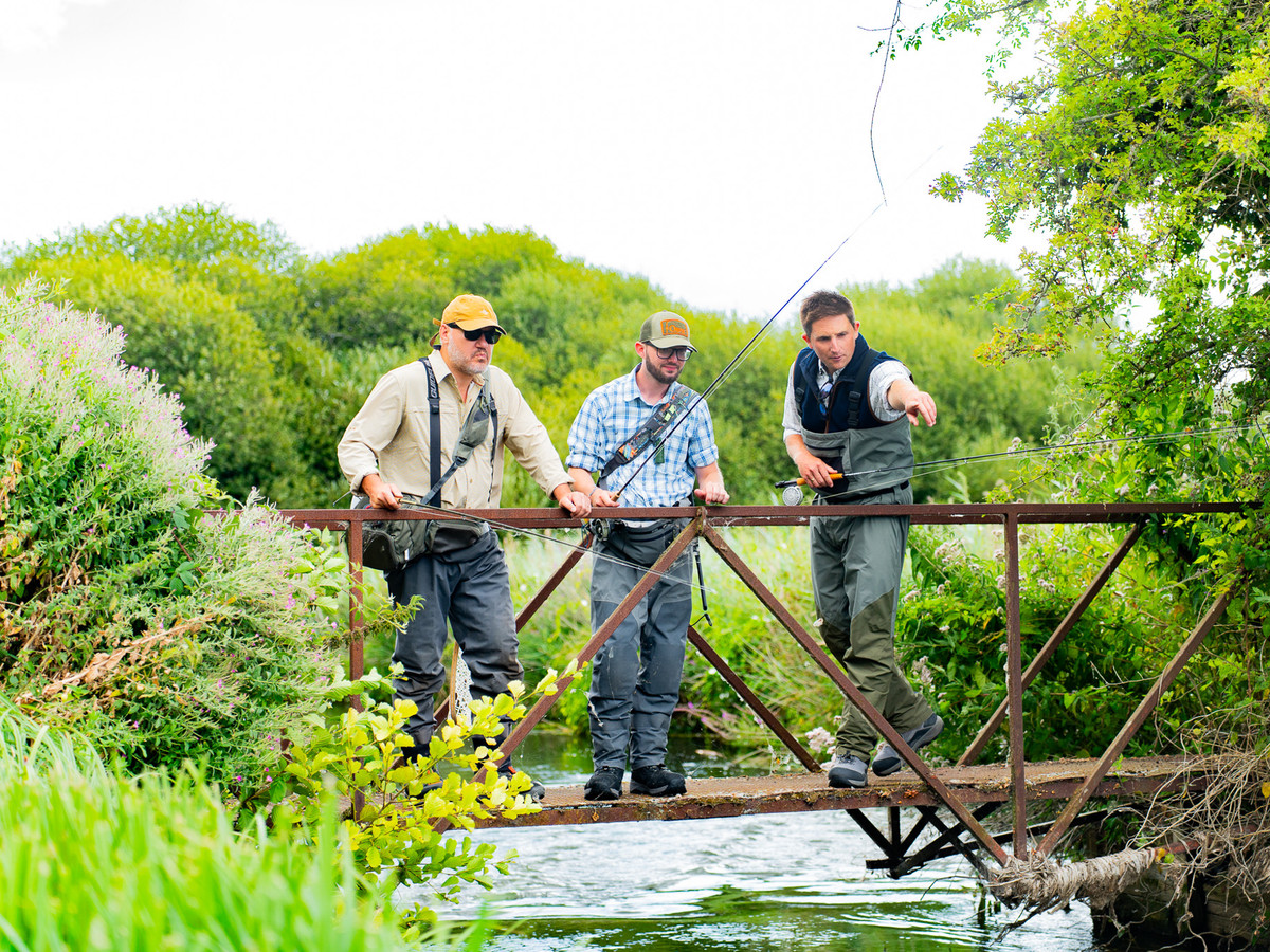 Jamie Pankhurst pointing at a brown trout from a bridge crossing the Lamb Stream
