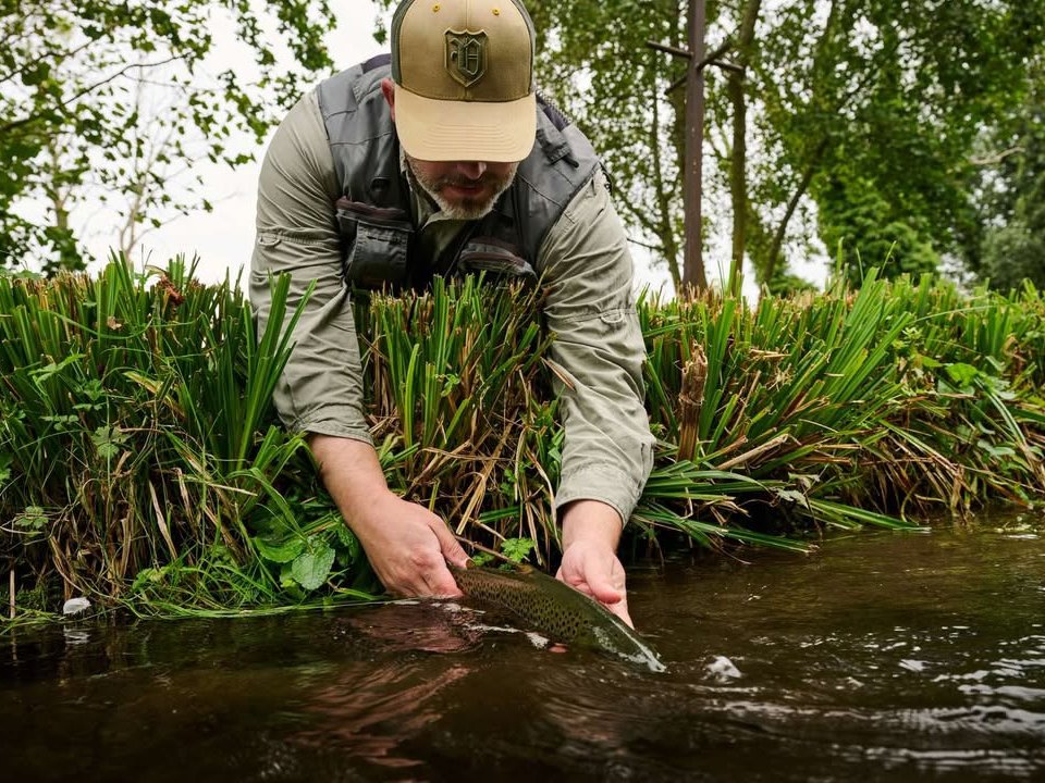 Ben Bangham releasing a trout by the bank